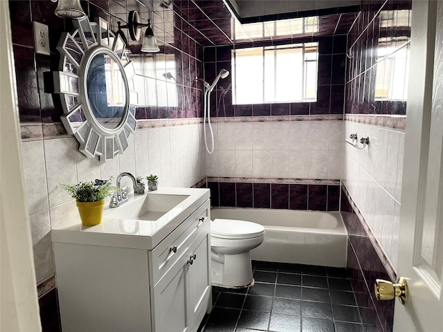 full bathroom with tile walls, tiled shower / bath combo, tile patterned floors, vanity, and toilet