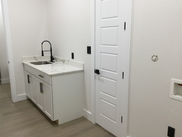 clothes washing area with hookup for a washing machine, light hardwood / wood-style flooring, and sink