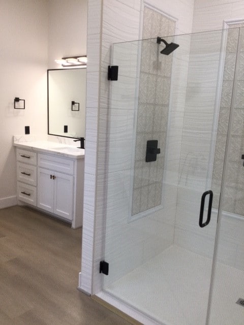 bathroom with vanity, an enclosed shower, and hardwood / wood-style flooring