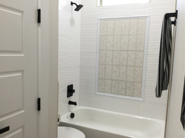 bathroom featuring tiled shower / bath combo and toilet