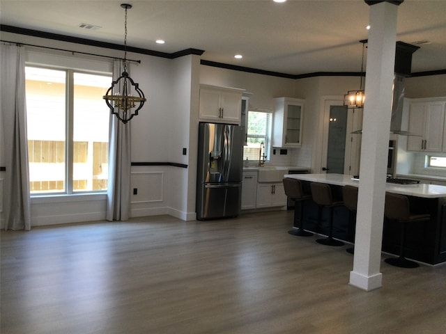 kitchen featuring white cabinetry, a breakfast bar area, pendant lighting, stainless steel refrigerator with ice dispenser, and hardwood / wood-style floors