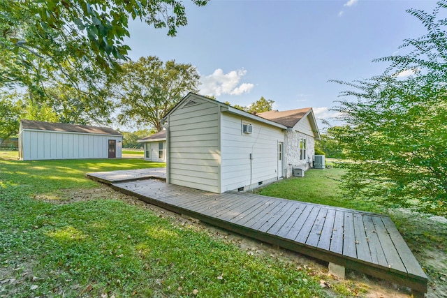 back of property featuring a storage shed, a deck, a yard, and central AC