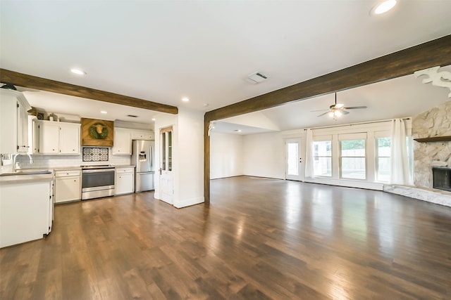 kitchen featuring appliances with stainless steel finishes, white cabinets, a fireplace, beamed ceiling, and ceiling fan