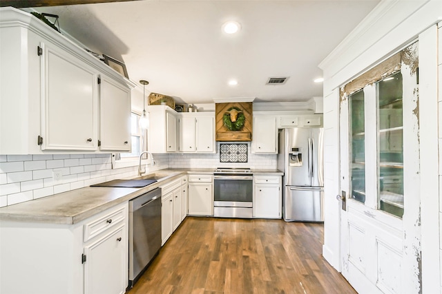 kitchen with appliances with stainless steel finishes, hanging light fixtures, dark wood-type flooring, tasteful backsplash, and white cabinets