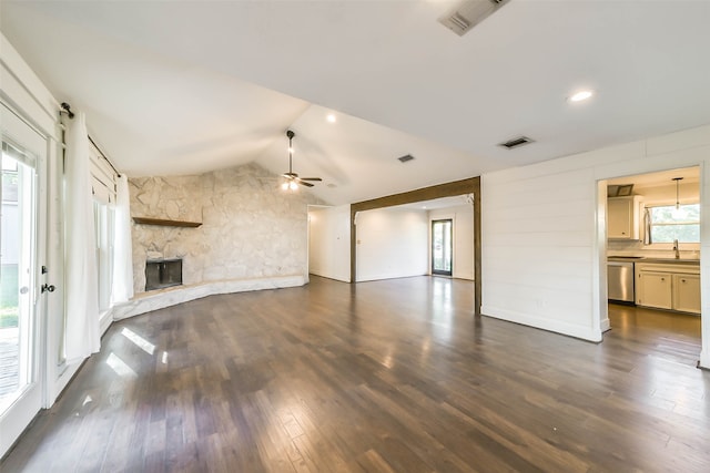 unfurnished living room featuring ceiling fan, a stone fireplace, lofted ceiling, and dark hardwood / wood-style floors