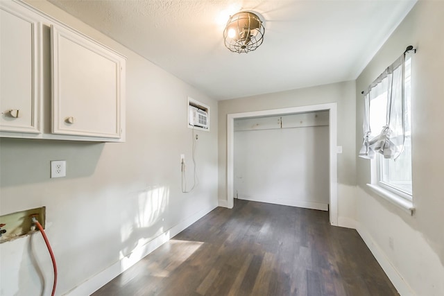 interior space with hookup for a washing machine, a textured ceiling, dark hardwood / wood-style floors, and a wall mounted AC