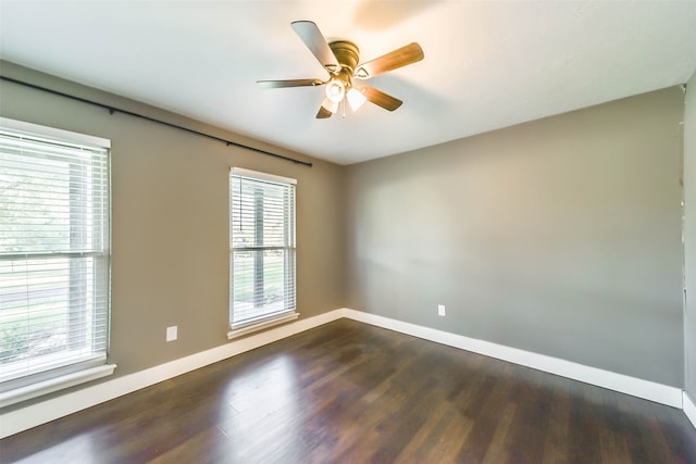 empty room featuring a wealth of natural light, ceiling fan, and dark hardwood / wood-style floors