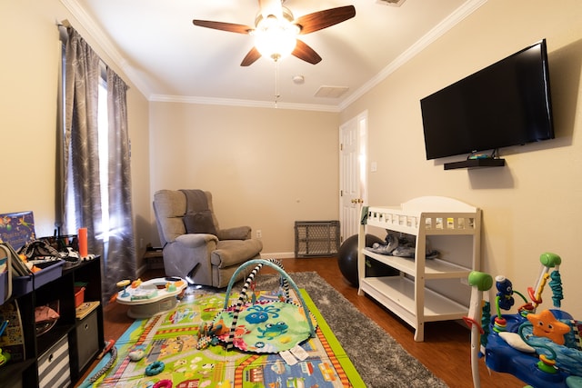 recreation room featuring ornamental molding, dark hardwood / wood-style floors, and ceiling fan