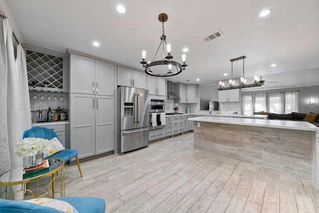 kitchen with pendant lighting, gray cabinetry, stainless steel appliances, and light wood-type flooring