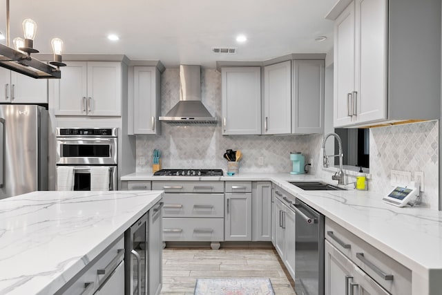 kitchen featuring sink, wall chimney exhaust hood, appliances with stainless steel finishes, and gray cabinetry