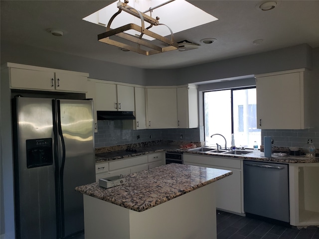 kitchen featuring tasteful backsplash, white cabinets, a kitchen island, stainless steel appliances, and sink