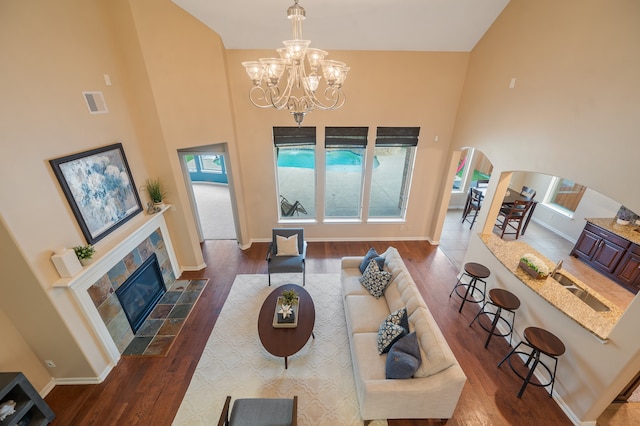 living room featuring a fireplace, a towering ceiling, dark hardwood / wood-style floors, and a notable chandelier