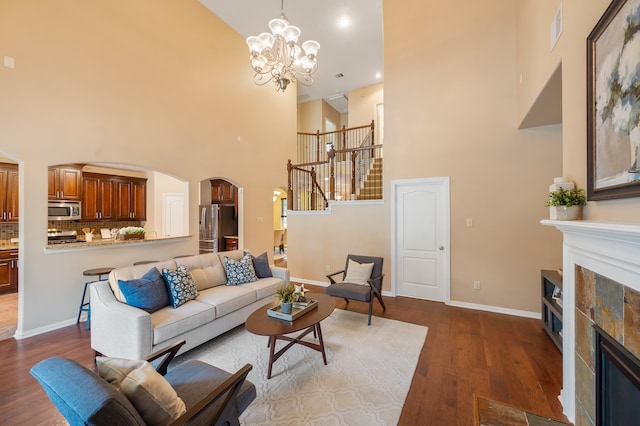 living room with an inviting chandelier, a high ceiling, hardwood / wood-style floors, and a fireplace