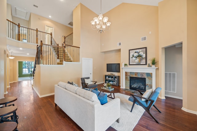 living room with dark hardwood / wood-style floors, an inviting chandelier, a tiled fireplace, and high vaulted ceiling