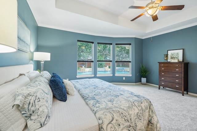 bedroom with ceiling fan, light colored carpet, a tray ceiling, and crown molding