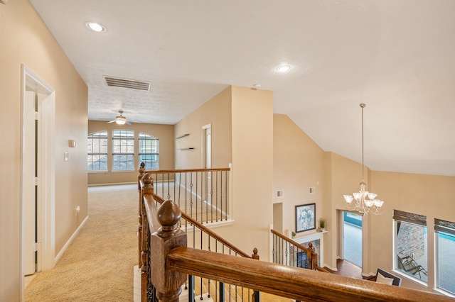 hallway with lofted ceiling, light carpet, and a chandelier