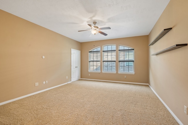 empty room featuring ceiling fan, light colored carpet, and a textured ceiling