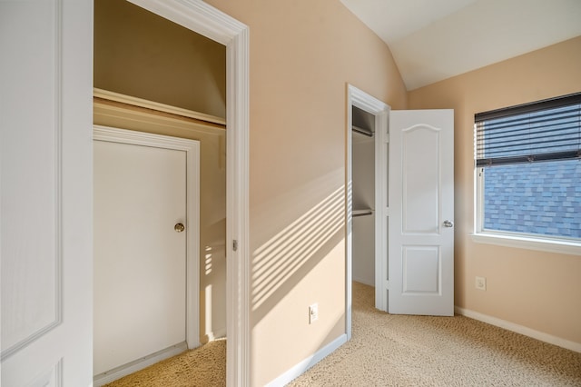 unfurnished bedroom with light colored carpet, a closet, and vaulted ceiling