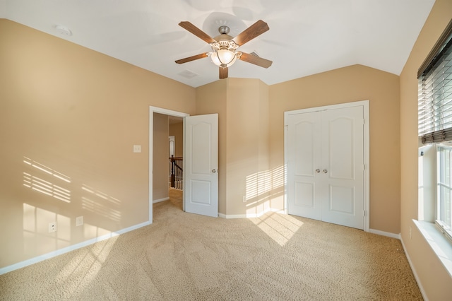 unfurnished bedroom with ceiling fan, light colored carpet, a closet, and lofted ceiling