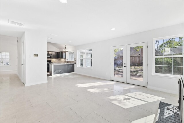 unfurnished living room with sink, light tile patterned floors, and french doors