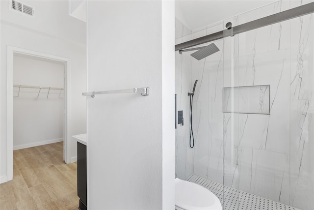 bathroom with wood-type flooring, walk in shower, vanity, and toilet