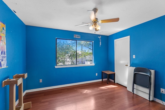 interior space with heating unit, ceiling fan, dark wood-type flooring, and a textured ceiling