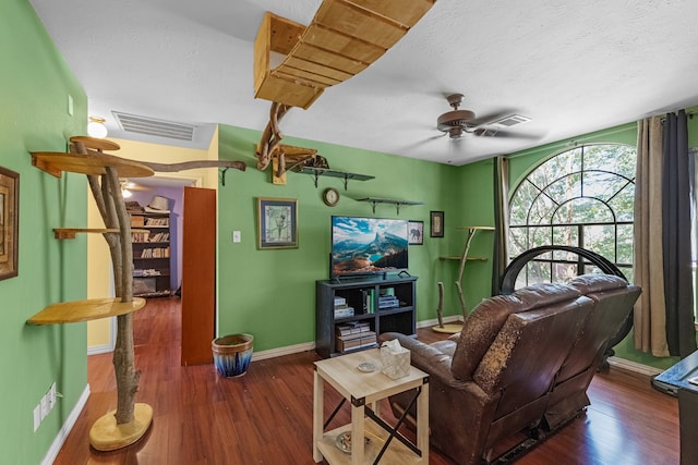 living room with a textured ceiling, dark hardwood / wood-style floors, and ceiling fan