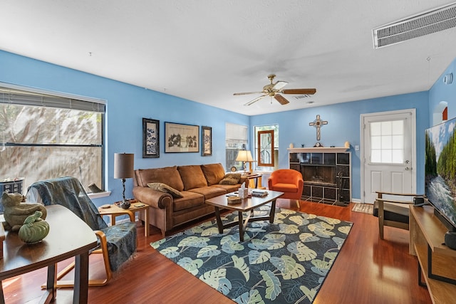 living room with ceiling fan, a fireplace, and dark hardwood / wood-style flooring