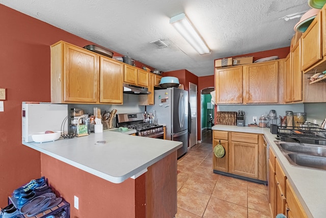 kitchen featuring appliances with stainless steel finishes, kitchen peninsula, light tile patterned floors, a textured ceiling, and sink