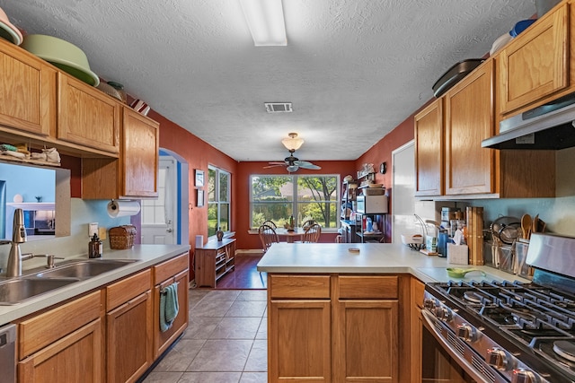 kitchen with appliances with stainless steel finishes, kitchen peninsula, a textured ceiling, sink, and extractor fan