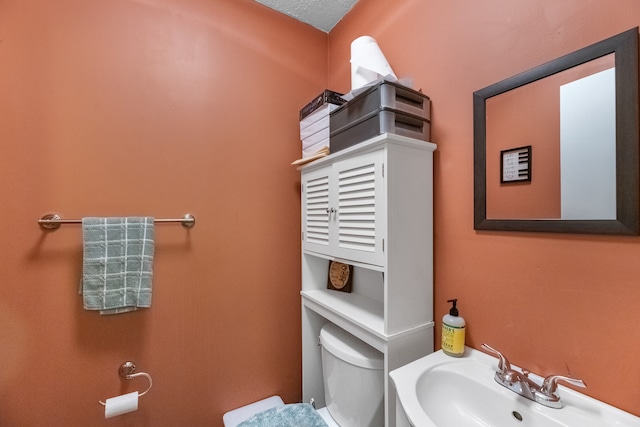 bathroom featuring a textured ceiling, toilet, and sink