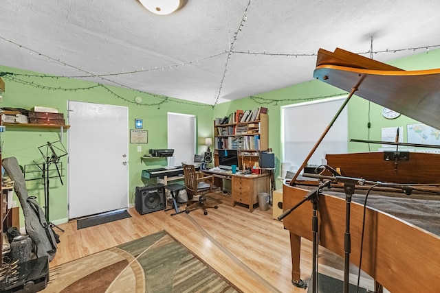 home office featuring a textured ceiling, vaulted ceiling, and hardwood / wood-style flooring