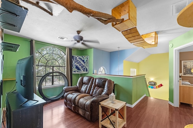 living room with a textured ceiling, ceiling fan, and dark wood-type flooring