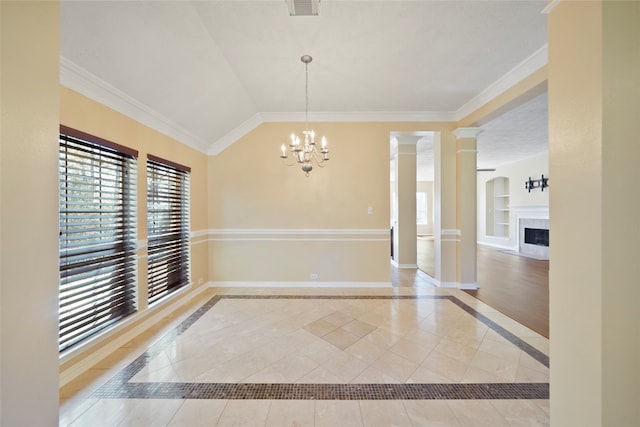 interior space featuring a chandelier, vaulted ceiling, a premium fireplace, crown molding, and built in features