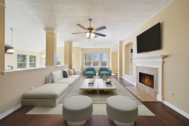 living room featuring a tile fireplace, hardwood / wood-style floors, ceiling fan, and a wealth of natural light