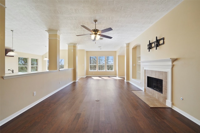 unfurnished living room featuring a textured ceiling, a tiled fireplace, dark hardwood / wood-style floors, and a wealth of natural light