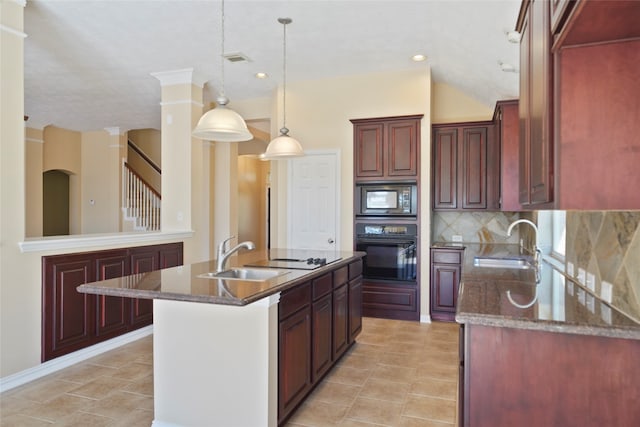 kitchen featuring tasteful backsplash, sink, hanging light fixtures, black appliances, and a center island with sink