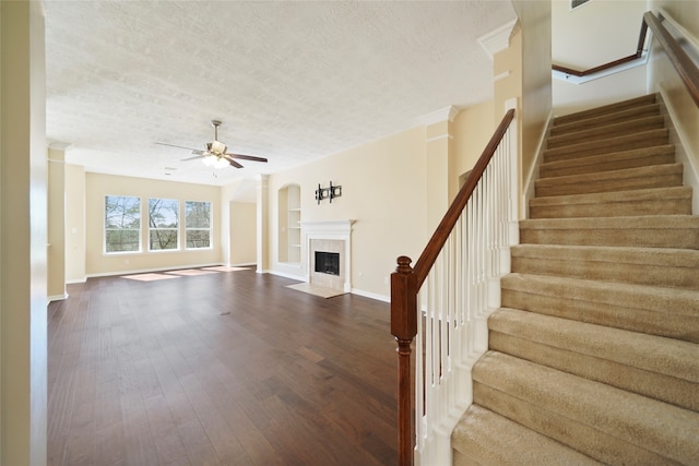 unfurnished living room with ceiling fan, a tile fireplace, hardwood / wood-style flooring, and a textured ceiling