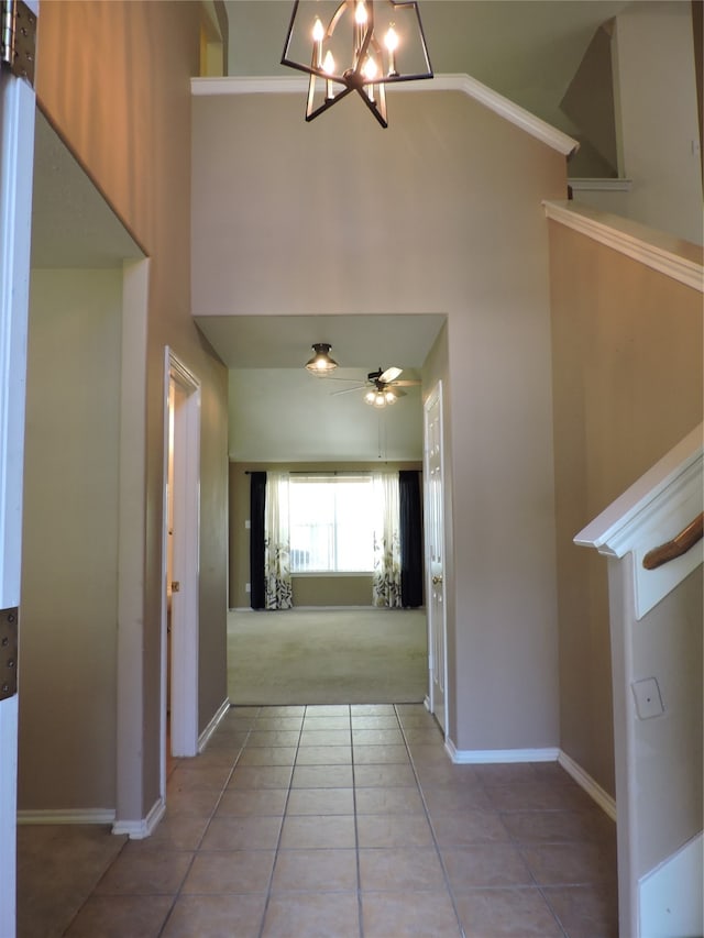 hallway featuring high vaulted ceiling, a notable chandelier, and light tile patterned floors