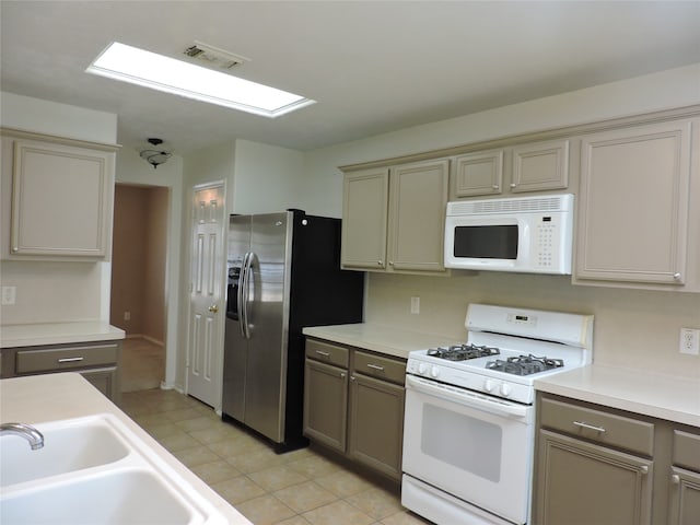 kitchen with white appliances, light tile patterned flooring, and sink