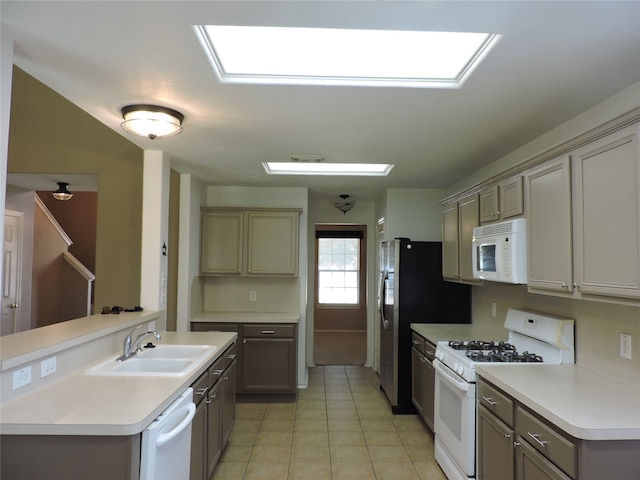 kitchen featuring white appliances, sink, light tile patterned floors, and kitchen peninsula