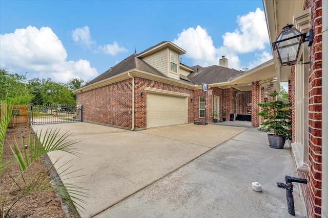 15026 Blossom Bay Dr, Houston, TX 77059 - view of home's exterior featuring concrete driveway, an attached garage, a gate, brick siding, and a chimney