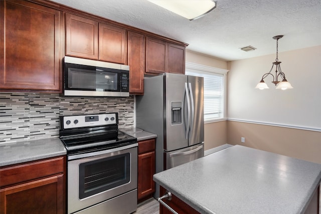 kitchen featuring appliances with stainless steel finishes, a textured ceiling, pendant lighting, and tasteful backsplash