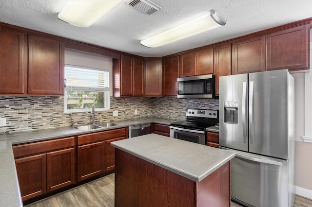 kitchen featuring light hardwood / wood-style floors, appliances with stainless steel finishes, sink, and a center island