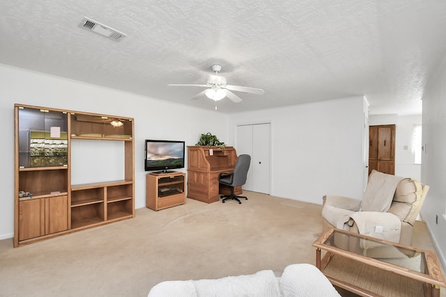 carpeted home office featuring ceiling fan and a textured ceiling