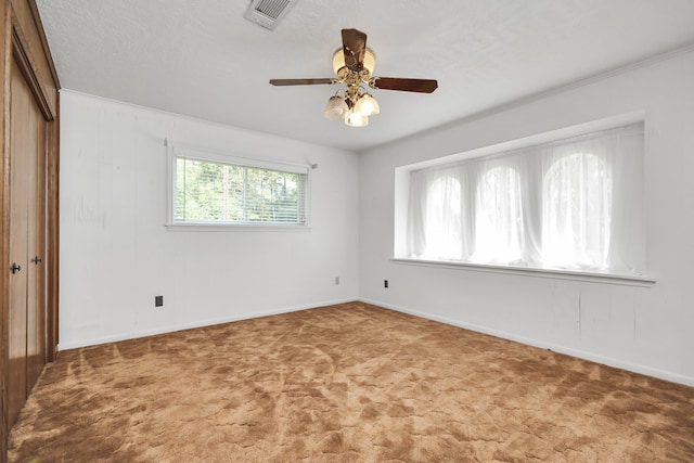 unfurnished room with carpet, ceiling fan, crown molding, and a textured ceiling