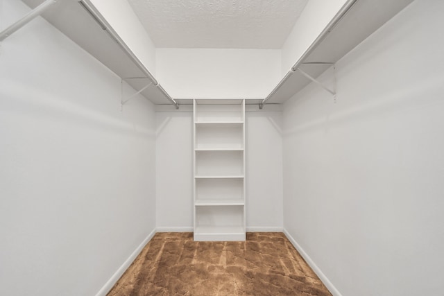 walk in closet with dark carpet