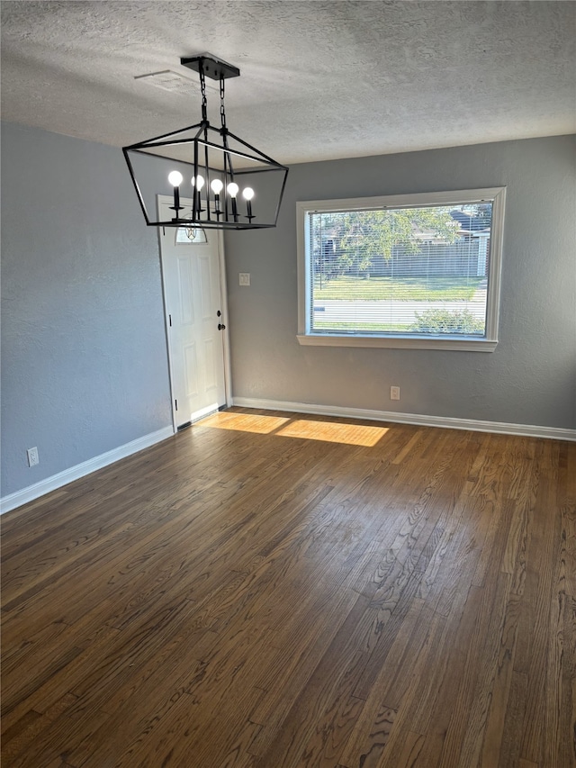 interior space featuring an inviting chandelier, dark wood-type flooring, and a textured ceiling