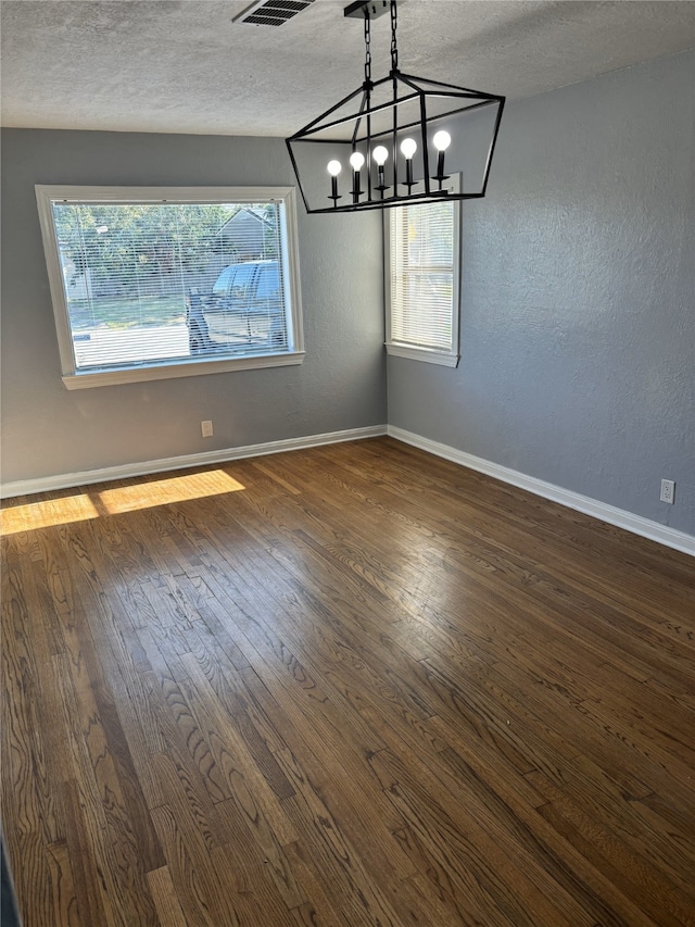 spare room featuring a textured ceiling, plenty of natural light, and dark wood-type flooring