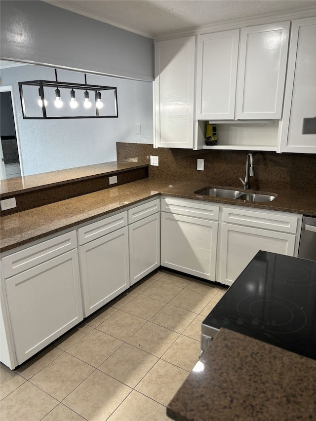 kitchen featuring hanging light fixtures, dark stone counters, sink, and white cabinets